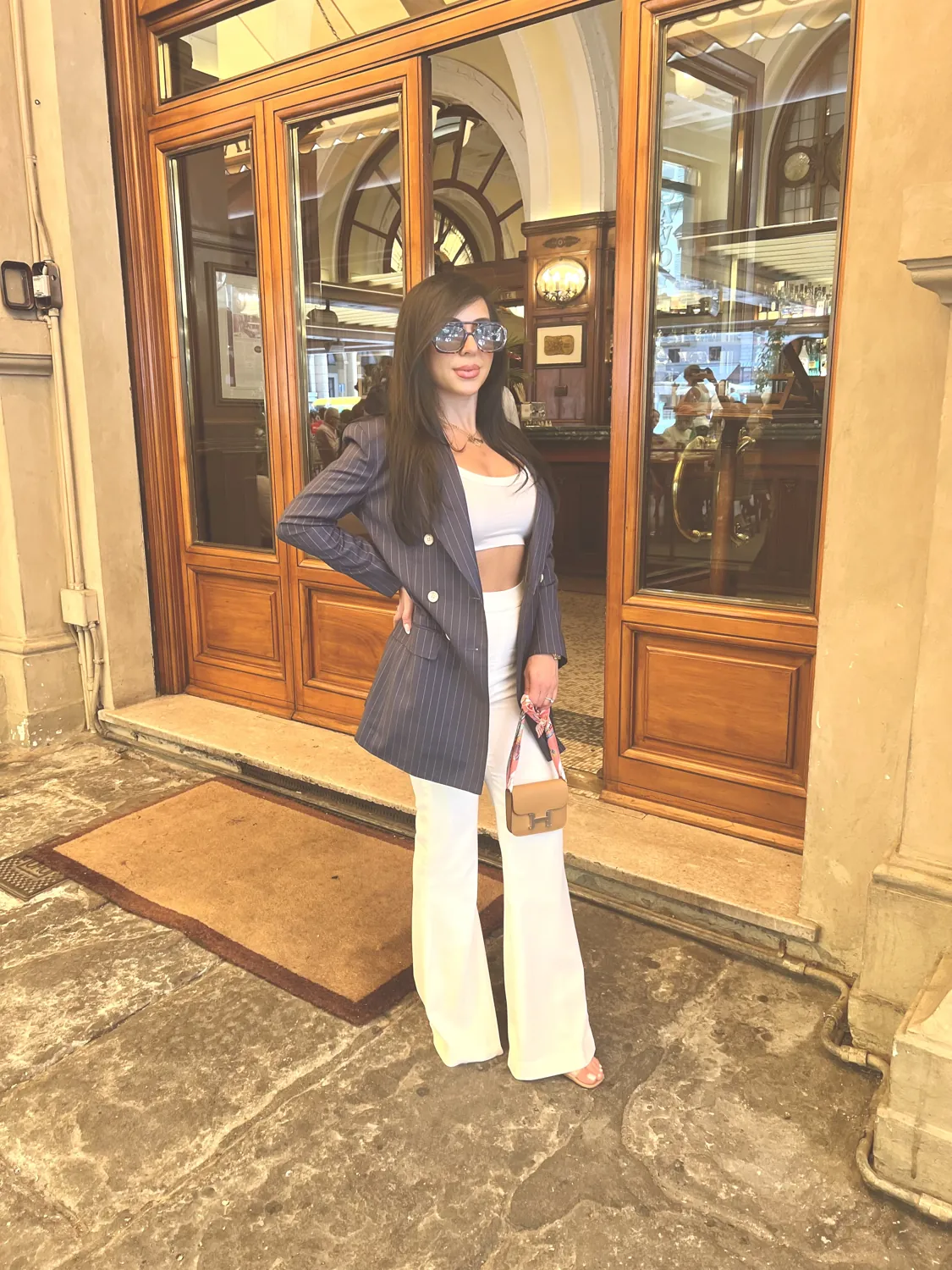 Natalie in a navy pinstripe blazer and white trousers.