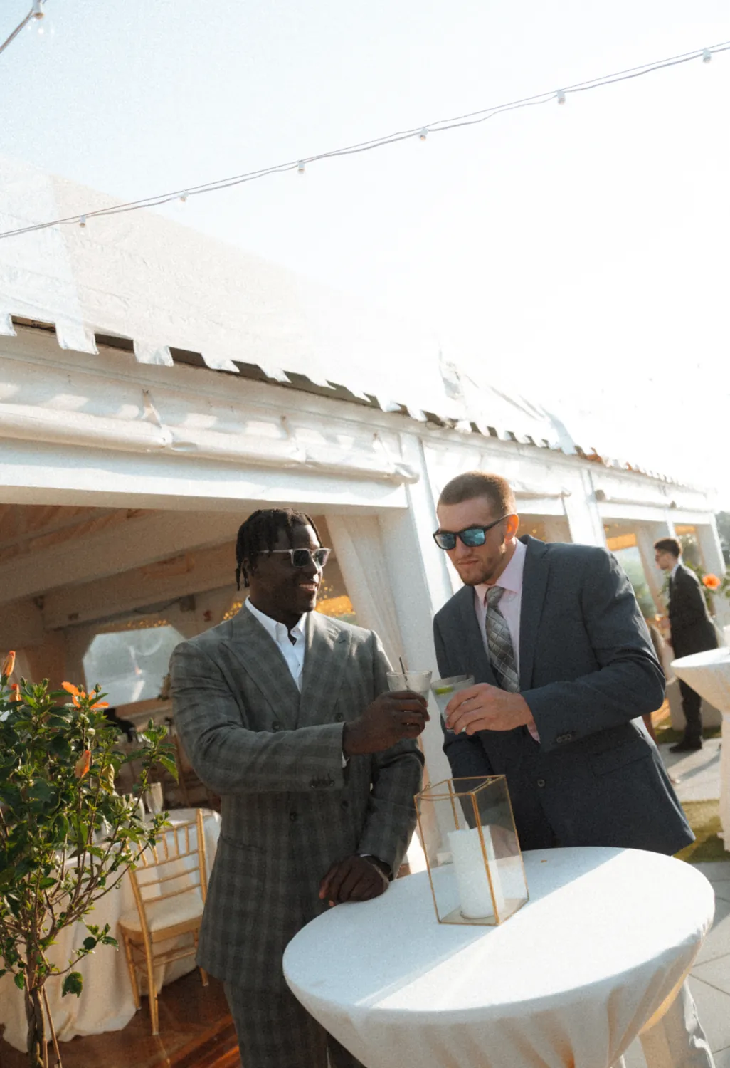 Two clients in made to measure suits raising glasses outdoors.