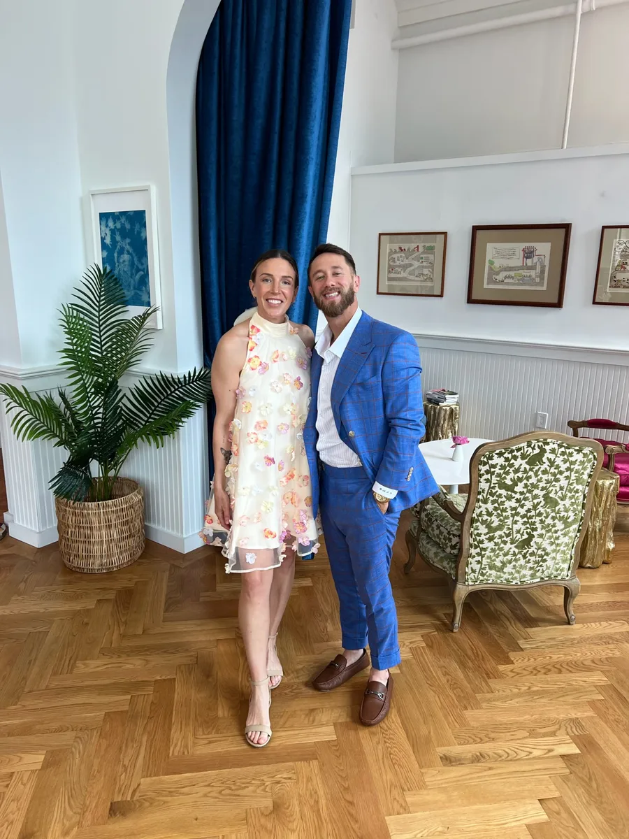 A client in a blue windowpane suit standing with a companion in a tea room.